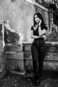 Full length of young woman standing by retaining wall