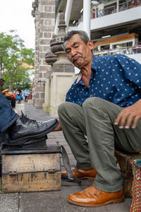 Low angle view of man sitting on street