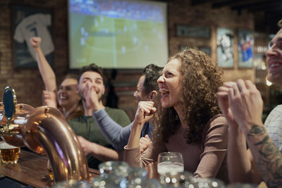 Happy friends watching soccer match at bar