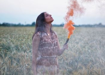 Young woman standing on field with a smoke granade 