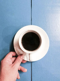 Close-up of hand holding coffee cup on table