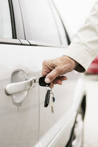 Cropped image of woman inserting key in car door