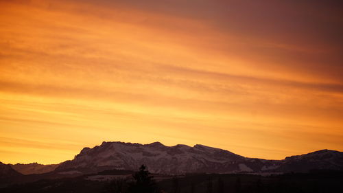 Scenic view of mountains against orange sky