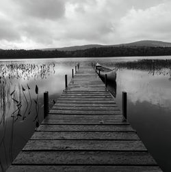 Wooden jetty on pier over lake against sky