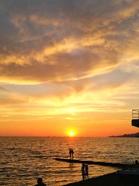 Silhouette people on beach against sky during sunset