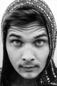 Close-up portrait of young man in hooded shirt against sky