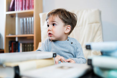 Cute boy with books on table at home