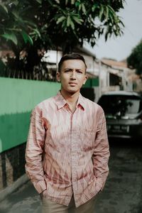 Portrait of young man standing against trees