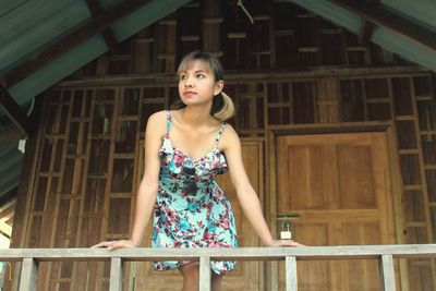 Portrait of woman standing against railing