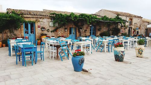 Empty chairs and tables on street by building