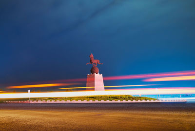 Monument amidst light trails against blue sky at night