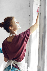 Side view of young woman looking through window