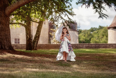 Little girl with long blond hair walks in the castle garden, with an umbrella 