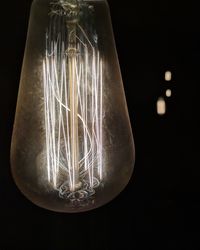 Close-up of illuminated light bulb against black background