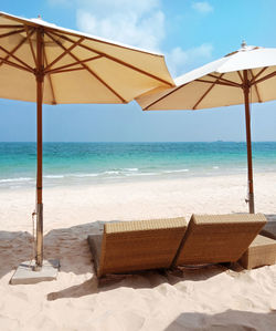 Deck chairs on beach against sky