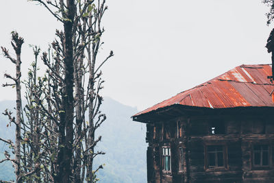 House and trees by lake against sky