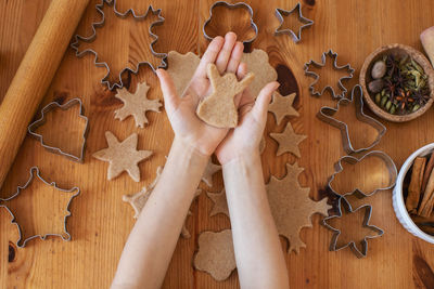 Children with their mother cut out christmas gingerbread cookies on the table from rolled dough. 