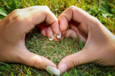 Close-up of hands playing with grass