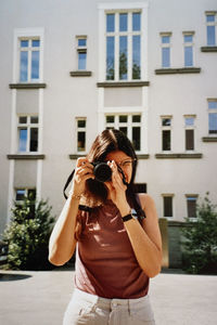 Young woman photographing through camera. young woman with camera in the city.