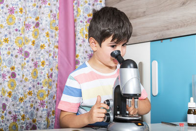 Caucasian boy examining preparation under the microscope.