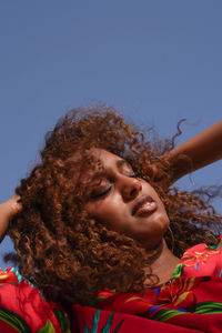 Portrait of woman with dark skin with long curly hair with eyes closed