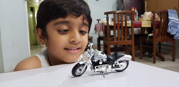 Close-up of boy looking at toy motorcycle on table