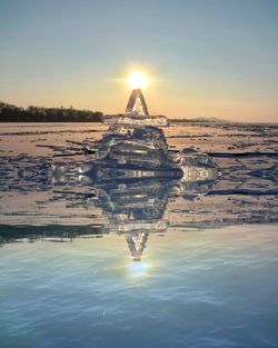 Man standing on shore against sky during sunset