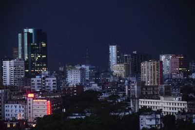 Illuminated buildings in city against sky at night