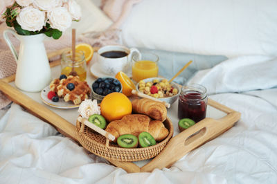 Romantic breakfast with coffee, waffles, orange juice and rose flowers.