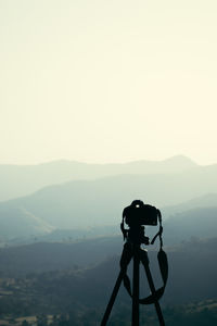 A camera mounted on a tripod pointing towards a landscape