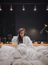 Portrait of smiling young woman sitting on bed