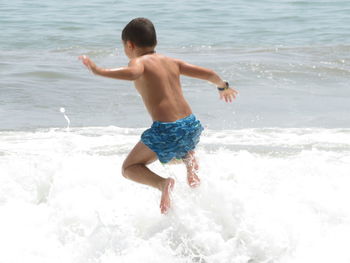 Rear view of shirtless boy in sea