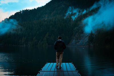 Rear view of man standing by lake