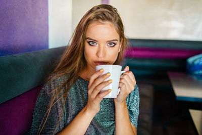 Portrait of young woman having coffee at home