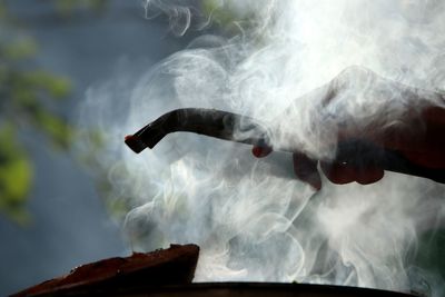 Close-up of hand with meat on barbecue