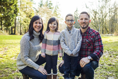 Family of four pose for photo in the park.