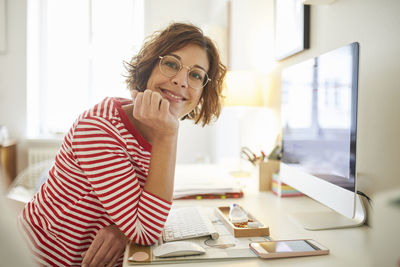 Portrait of content mature woman sitting at desk at home