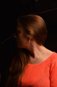 Close-up of young woman against black background