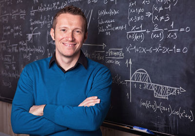 Portrait of smiling man against blackboard