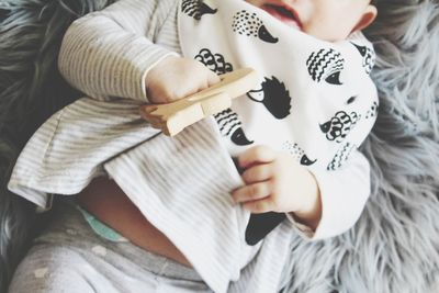 Baby dressed in monochrome colors laying on its back holding a teether.