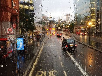 Cars on city street seen through wet glass window