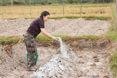 Woman putting fertilizer while standing on agricultural field