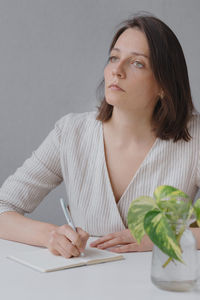 Portrait of young woman using mobile phone while sitting on table