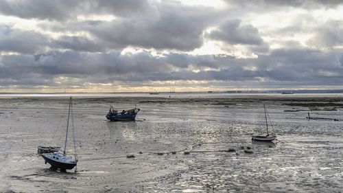 Boat moored on sea against sky during sunset