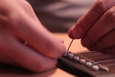 Close-up of hand stringing guitar