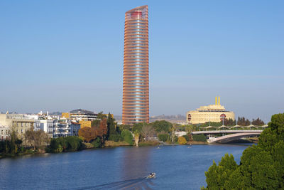 Buildings by river against sky in city