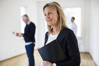 Thoughtful real estate agent with colleague and man in background at home