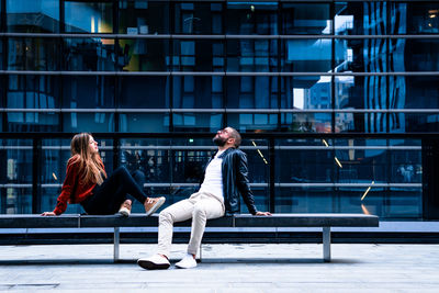Woman sitting on bench in city