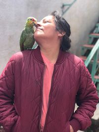 Young woman carrying bird on shoulder outside house