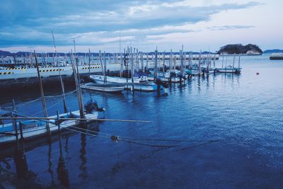 Boats moored at harbor against sky